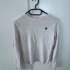 Ljusrosa ribbad tröja från Bondelid - Säljer en ljusrosa ribbad tröja från Bondelid i storlek XS. Tröjan har ett diskret rutmönster, rund halsringning och lång ärm. Liten broderad logga på bröstet. Perfekt för lager-på-lager under kyligare dagar.