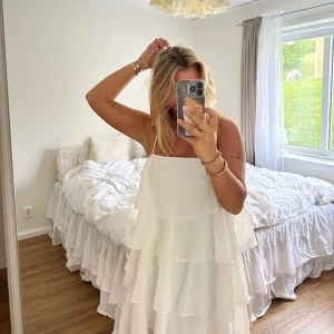 Volangklänning  - Supersöt vit klänning med volanger och smala knytbara axelband. Den är från Gina Tricot och är hyfsat kort i längden. Aldrig använd. Storlek 36, köpt för 699 kr