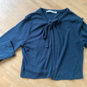 Svart kofta med knyt från 157 - Mörkblå kofta från 157 med snygg knytning framtill vid halsen. Mjuk och skön tröja enkel att styla säljer eftersom att den inte kommer till så mycket andvändning. 