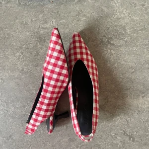 Gingham pumps med spetsig tå - Snygga pumps med gingham mönster och spetsig tå. Skorna har låg klack och öppen häl med rem, vilket ger en cool retrovibe. Perfekta för dig som vill sticka ut med ett lekfullt och trendigt par skor. Använts en gång. 