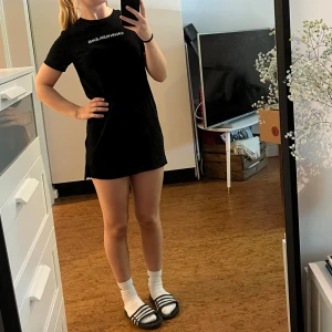 Svart t-shirtklänning Calvin Klein Jeans - Svart t-shirtklänning från Calvin Klein Jeans med vit logga framtill. Rak och kort modell med rund hals och korta ärmar. Tillverkad i mjuk bomull, perfekt för en chill och stilren look. Använd men fortfarande i väldigt bra skick. 