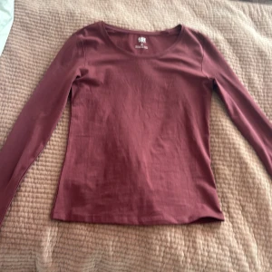 Mörkröd långärmad topp från 157 - En basic mörkröd långärmad topp från 157 i stretchig bomullsblandning. Modellen är figurnära med rund halsringning och passar perfekt till jeans eller kjol. Materialet är mjukt och skönt, 95% bomull och 5% elastan. Aldrig använd, köpte utan att testa och den passa ej. Passar perfekt med en kofta