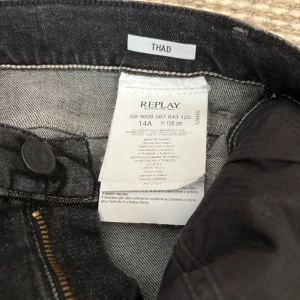 Svarta Replay jeans, modell Thad - Snygga svarta jeans från Replay, modell Thad. Jeansen har klassisk femficksdesign, dragkedja och knapp framtill för en cool look. Passar dig som gillar stilrena och bekväma jeans med en modern touch. Har bara användt de en gång