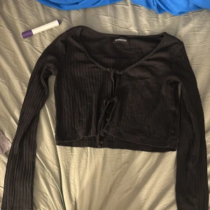 En svart tröja  - Den är öppen fram där man kan knyta den, lappen är borta men skulle gissa att den är i M och är väldigt stretchig