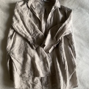 Beige skjorta/blus Zara XS - Snygg beige linnen skjorta från Zara. Den är oversized och i storlek XS. Den har använts få gånger och är i superbra skick. Perfekt nu till sommaren. 