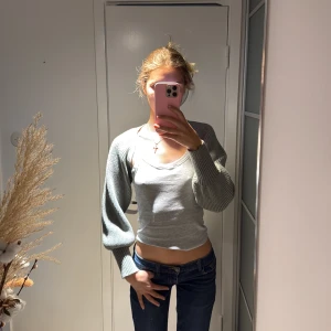 Grön ribbad bolero från Zara  - Säljer en grön ribbstickad bolero från Zara med långa, ballongformade ärmar. Perfekt att slänga över ett linne eller t-shirt för en cool lager-på-lager-look. Materialet är mjukt och stickat, och passformen är loose. Superenkel att styla till jeans eller kjol.