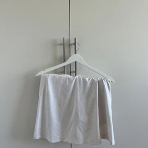 Vit kortkjol från Röhnisch - Snygg vit kortkjol från Röhnisch med diskreta små prickar och dragkedja i sidan. Kjolen har en enkel och clean look, perfekt för dig som gillar sportig stil. Lätt och bekväm att bära, passar till många olika outfits.