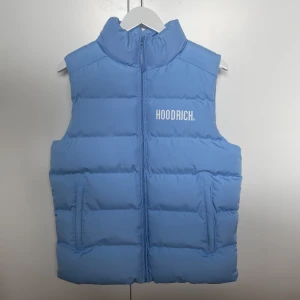 Hoodrich Väst - Snygg ljusblå dunväst från Hoodrich med stor logga på ryggen och mindre tryck framtill. Oanvänd med kvitto och tag.