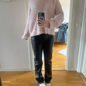 Svarta raka byxor i skinnimitation - Snygga svarta byxor i skinnimitation med rak passform och klassisk femficksdesign. Byxorna har normal midja och stängs med dragkedja och knapp. Perfekta för dig som vill ha en edgy och stilren look.