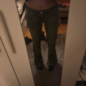 True Religion bootcut jeans blå - Säljer ett par klassiska blå bootcut jeans från True Religion med snygga detaljer på bakfickorna och låg midja. Jeansen har fem fickor, synliga sömmar och ikonisk logga på bakfickan. Perfekta för dig som gillar en avslappnad men trendig look.