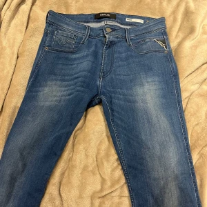 Replay Anbass - Snygga blå Replay Anbass jeans i slim fit med detaljer på bakfickorna.Jeansen har en lätt tvättad look och är tillverkade i mjukt denimtyg som sitter skönt hela dagen. Jeansen är i väldigt bra skick, köpta för omkring 1200 mitt pris 500 