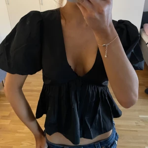Svart blus med puffärmar - Snygg helt ny svart blus med puffiga kortärmar och v-ringning. 