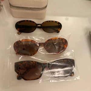 Tre par solglasögon med leopardmönster - Säljer tre par solglasögon med leopardmönster. Ett par har en oval form med mörka linser, det andra paret är rundare med bruna linser, och det tredje paret har en mer kantig design. Perfekta för att ge din stil en cool touch!