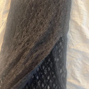 Svart långkjol från Sofie Schnoor - Elegant svart långkjol från Sofie Schnoor med ett coolt spetsmönster och en kort svart kjol under. Perfekt för speciella tillfällen med sin långa och sofistikerade design. Använt fåtal gånger så jättebra skick. Väld