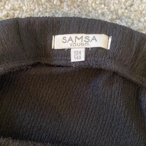 Svart kjol från Samsa Young - Snygg svart kjol från Samsa Young med volangdetalj.  Den är använd en gång så inga defekter, är i storlek 134/140 men passar som XS