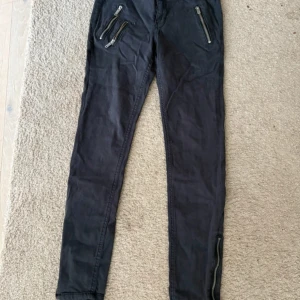 Svarta jeans med dragkedjor - Snygga svarta jeans med coola dragkedjor på fickorna och vid bensluten. Perfekta för en edgy look. De har en tight passform och är tillverkade i ett bekvämt material som ger en skön känsla hela dagen.
