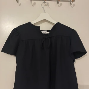 Mörk blå blus, perfekt för en varm vårdag✨ - Säljer en stilren blå blus från kappahl med korta ärmar och en söt knytning framtill. Perfekt för både vardag och lite finare tillfällen. Blusen har en lös passform och är tillverkad i ett lätt och bekvämt material.