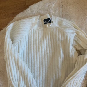Vit ribbad tröja från Pieces - Säljer en stilren vit ribbad tröja från Pieces. Tröjan har långa ärmar och en klassisk rund halsringning. Perfekt för en avslappnad och bekväm stil. Passar bra till både jeans och kjol.