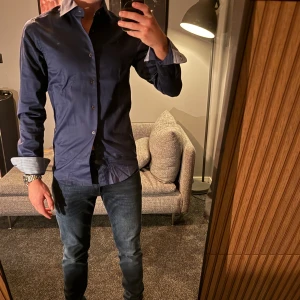 Mörkblå skjorta ifrån Dressmann - Riktigt snygg och stilren mörkblå skjorta från dressmann, den är i väldigt bra skick. Endast använd 1 gång. Den är i storlek xs och har en slim fit passform och jag som bär denna är 174cm lång. Köpt för 599kr. Bara att höra av dig om du har några funderingar 🙌🏼Pris går att diskuteras vid snabb och smidig affär. 