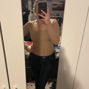 Beige topp - Säljer en beige topp med långa ärmar och snörning i sidan. Toppen har en tight passform och är perfekt för en stilren look. Den är både bekväm och snygg.💖