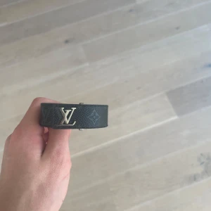 Lv slim braclet (Kvitto Finns !!) - Svart armband Louis vuitton i storlek 21cm. Det finns tre olika  hål så du kan justera storleken . Nypris 3200 mitt pris 1299. Kvitto finns att visas , säljs billigt pågrund av att det inte finns någon låda och att jag bli av med den! .