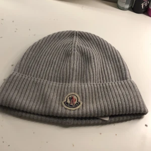 Moncler mössa - Hjälper min kille att sälja.                                             Grå äkta moncler mössa köpt på deras egna hemsida för 2960kr för ungefär 2 månader sen, säljer för jag inte använder den längre, kvitto finns