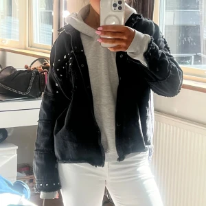 Svart jeansjacka med nitar - Cool svart jeansjacka från Zara med nitar på axlarna och ärmsluten. Jackan har en avslappnad passform och knappar framtill. Perfekt nu till våren och sommaren!