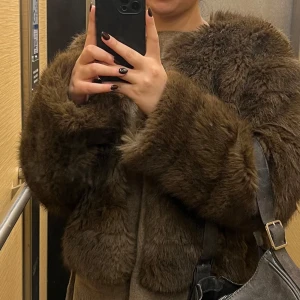 Brun pälsjacka - Säljer en mysig brun pälsjacka med långärmade ärmar. Perfekt för kyliga dagar när du vill hålla dig varm och stilren. Jackan har en lyxig känsla och passar bra till olika tillfällen.