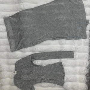 Glittrigt set från C.W. - Säljer ett glittrigt set från C.W. Storlek XS på tröjan och M på kjolen.  Setet har en tight passform och långa ärmar, perfekt för en festlig kväll. Materialet är syntetiskt och ger en skimrande effekt. Passar utmärkt för nyår eller andra speciella tillfällen. ✨