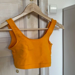 Orange/gul topp från Gina Tricot - Säljer orange/gul topp från Gina Tricot. Toppen är ärmlös och har en enkel design som passar perfekt till sommaren. 