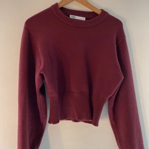 Vinröd stickad tröja från Zara - Säljer en vinröd stickad tröja från Zara. Tröjan har en åtsittande design vid midjan med ribbade muddar vid ärmslut och nederkant. Perfekt för vardag och fest. Passformen är väldigt fin och materialet är bra💘💕