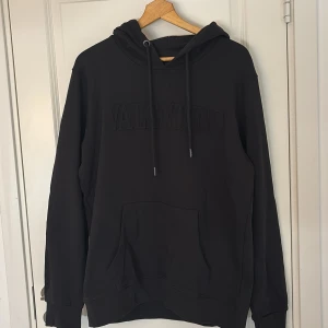  Valentino hoodie - Säljer en stilren svart hoodie från Valentino med en diskret logga på bröstet. Tröjan har en klassisk känguruficka och justerbar huva med dragsko. Perfekt för en avslappnad och trendig look.