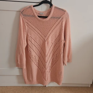 Rosa stickad tröja med mönster - Säljer en söt rosa stickad tröja med ett detaljerat mönster framtill. Tröjan har trekvartsärmar och en rund halsringning. Perfekt för en mysig dag.
