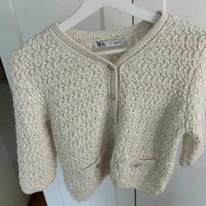 Beige stickad kofta från Zara - Säljer en beige stickad kofta från Zara med guldiga detaljer då den nu är för liten. Koftan är anvönd en gång och väldigt bra kvalitet!
