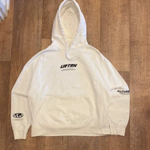 Vit Hoodie från YOURTURN Storlek XS - Säljer en stilren vit hoodie från YOURTURN med tryck på bröstet och ärmen. Den har en klassisk känguruficka och en bekväm huva med dragsko. Perfekt för en avslappnad stil. Storlek XS passar Small. Snabb Leverans!