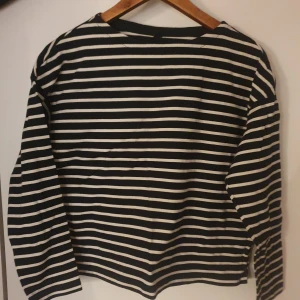 Svartvit randig långärmad tröja - Säljer en stilren svartvit randig tröja med långa ärmar. Perfekt för en avslappnad look. Tröjan har en normal passform och är tillverkad i ett mjukt material.