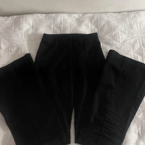 Svarta  kostymbyxor från Monki - Snygga svarta byxor från Monki i storlek 34. De har en klassisk design med en rak passform och är perfekta för en stilren look. Tillverkade i ett bekvämt material som passar till många olika tillfällen.