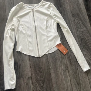 Vit långärmad topp med dragkedja - Snygg vit topp med lång ärm och dragkedja framtill. Superfin passform och skön att ha på sig, antingen som topp eller också som kofta med något på sig under🌸
