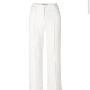 Vita kostymbyxor från Venderbys - Vita kostymbyxor från Venderbys med hög midja och raka ben. Byxorna har en stilren design med pressveck och dragkedja fram. Aldrig använda. Nypris 680kr