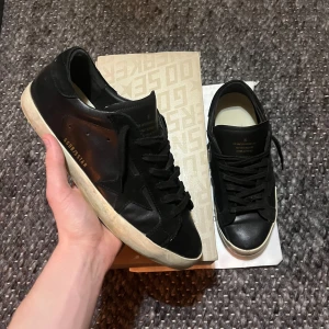 Svarta Golden goose skor - Säljer ett par svarta Golden goose i superstar modellen🤩storlek 43 men passar 44! Box, dustbag medkommer! Tveka inte av höra av er vid minsta fundering! Lite defekter därav priset!! Är öppen för prisförslag samt byten🤝skriv pm för kvittot!!