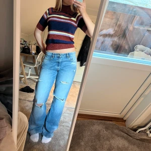 Randig kortärmad polotopp - Säljer en snygg randig polotopp som är glittrig.  Toppen är kortärmad och croppad, perfekt för en trendig look. Passar bra till jeans eller kjol. Hör av dig vid intresse!