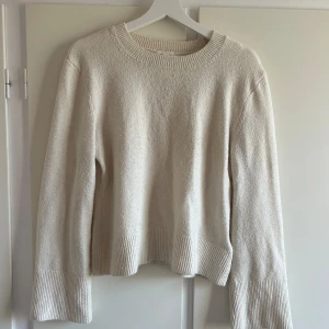 Vit stickad tröja - Säljer en mysig stickad tröja med rund hals och långa ärmar. Ribbade detaljer vid hals, ärmslut och nederkant. 