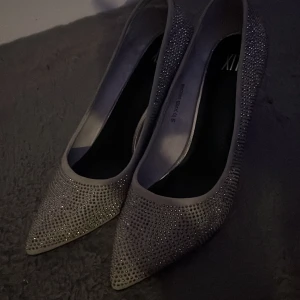 Glittriga pumps med spetsig tå - Snygga pumps i silver med glittriga detaljer och spetsig tå. Perfekta för att ge en extra touch till din outfit. Skorna har en elegant klack som ger en stilren look. Nypris 799 endast provade 