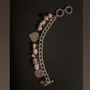 Charmigt armband med hjärtan och pärlor - Snyggt armband i silver med flera hängande detaljer som hjärtan och rosa pärlor. Perfekt för att ge en extra touch till din stil.