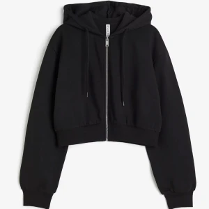 Svart croppad hoodie  - Säljer en svart croppad hoodie med dragkedja och huva. Perfekt för en avslappnad stil. Hoodien har långa ärmar och ribbade muddar vid ärmslut och nederkant. Passar perfekt till jeans eller leggings. 🖤hoodien är i samma modell som de första bilderna fast med en svart dragkedja som ni kan se på de andra bilderna! Använd 1 gång och har inga defekter💗