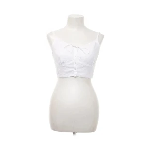 Vit linnetopp från NA-KD - Säljer en söt vit linnetopp från NA-KD med blommig textur. Toppen har ett snöre och knappar längs framsidan. 