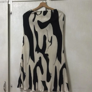 Plisserad svartvit kjol från SHEIN - Säljer en plisserad långkjol från SHEIN i svart och vitt med abstrakt mönster. Kjolen har lös passform och är ärmlös, perfekt för dig som gillar unika prints och stilren design.