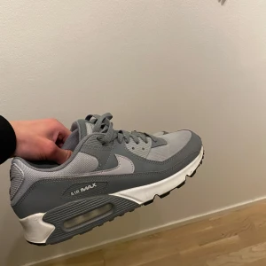 Nike Air Max 90 grå  - Säljer ett par Nike air Max skor i storlek 42,5, Rena och i bra skick förutom på baksidan då den är lite sliten. Skick 7/10, köpte för 1600 säljs för 1000kr 