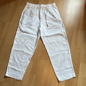 Linnebyxor från Zara - Säljer ett par vita linnebyxor från Zara i storlek M. Byxorna har elastisk midja och loose passform. De är perfekt nu inför sommaren. 100% linne.   Har för många byxor så dessa har använts rätt lite och är alltså i väldigt bra skick. Har du frågor eller funderingar är de bara att fråga! 