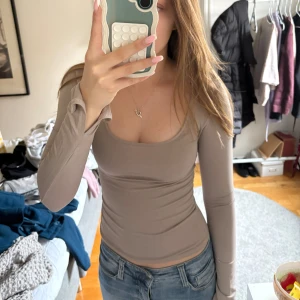 Beige långärmad topp från Gina Tricot - Säljer en beige långärmad topp från Gina Tricot. Toppen är tight och har en rundad halsringning samt slitsar i armarna. Perfekt att styla med jeans eller kjol för en enkel och snygg look. Stretchig 
